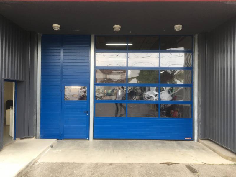 Pose de porte sectionnelle bleue sur façade d'entreprise
